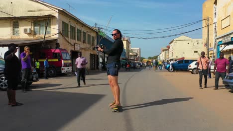 un turista patina por una calle en gambia áfrica occidental en una patineta