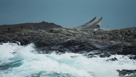 el puente de storseisundet se arca con gracia sobre la costa rocosa, enmarcada por las olas inquietas del océano atlántico.