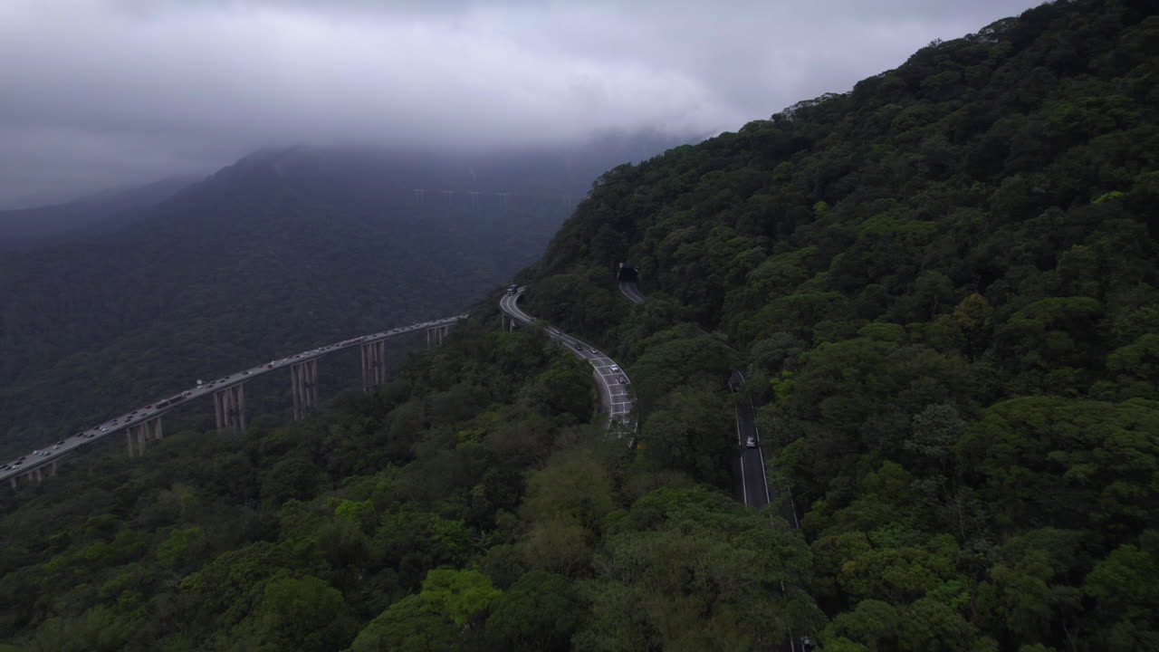 Aerial view following traffic driving high altitude in the Mata atlantica rainforest, gloomy Brazil