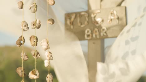 cloth waving in breeze and sea shells on string swaying at yoga bar, rack focus