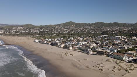 Parallel-drone-flyby-of-Ventura,-California-beach,-showcasing-tranquil-waves,-beachfront-properties,-and-cityscape