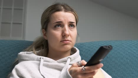 woman changing channels feeling bored on sofa