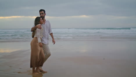 Loving-couple-going-evening-sea-shore-vertical.-Married-people-embracing-ocean