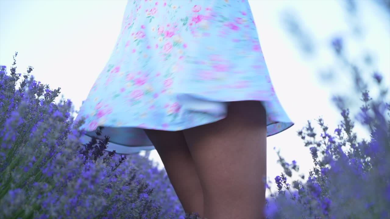 Woman in a blue floral dress spinning through a lavender field at sunset