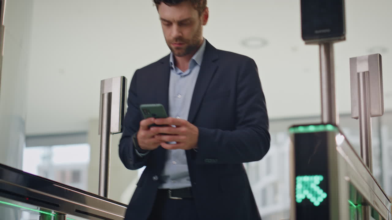empresario ocupado pasando por el torniquete enviando mensajes de texto al teléfono inteligente. gerente usando reloj inteligente