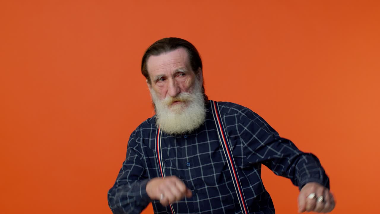 트렌디하고 긍정적 인 노인 남자가 재미있게 춤을 추고, 손을 들어 올리고, 댄스 몸짓을 합니다.