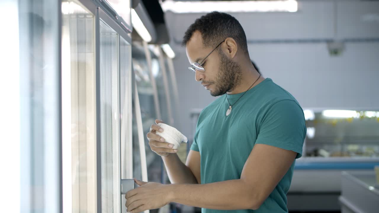 hombre afroamericano pensativo haciendo compras en la tienda de comestibles