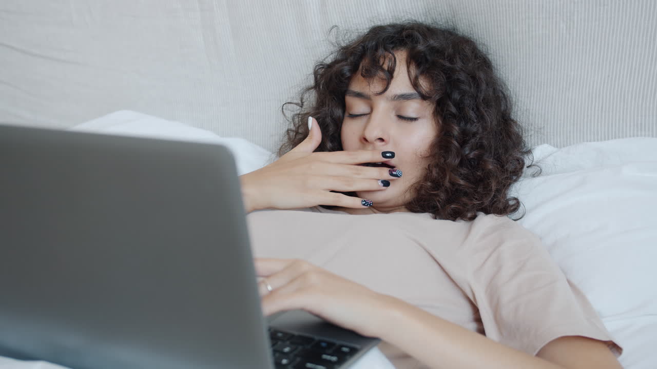 침대에 노트북으로 일하는 여자