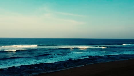 Luftaufnahmen,-Die-Mit-Einer-Drohne-Gefilmt-Wurden,-Mit-Blick-Auf-Den-Strand-Und-Das-Meer-Aus-Tosenden-Wellen-Mit-Einem-Tiefblauen-Ozean-Auf-Der-Klippe-In-Der-Südlichen-Hemisphäre-Afrikas