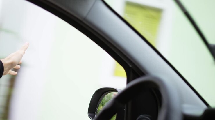 Unrecognizable man is catching the wind while driving a car by street