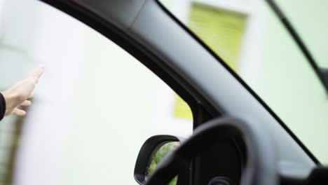 hombre irreconocible está atrapando el viento mientras conduce un coche por la calle