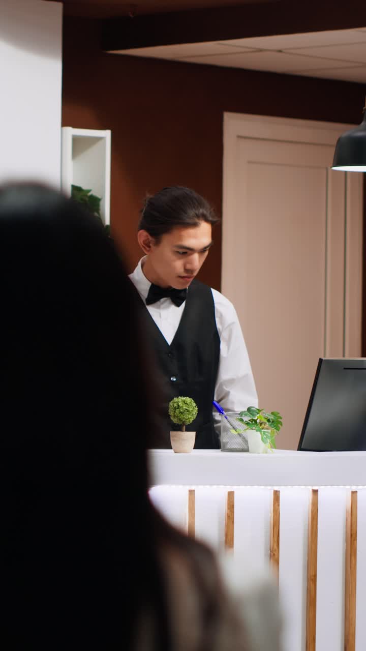 Video verticale: personale della reception che accoglie un ospite in hotel