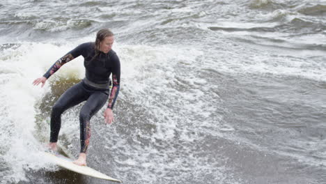 woman athlete - surfing on a river wave