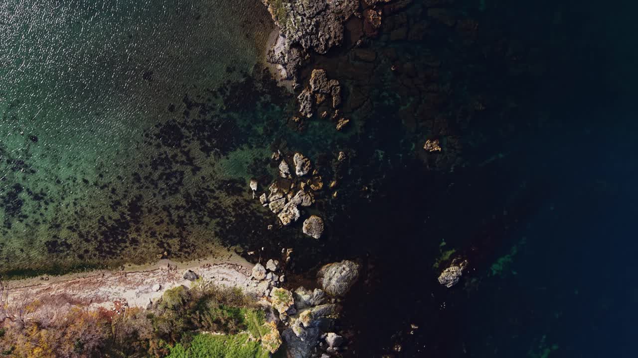 Scenic aerial view of rocky coastline meeting clear blue ocean waters
