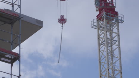 Tower-Crane-Pulley-And-Lifting-Chain-Hanging-And-Swinging-In-The-Air-Against-Cloudy-Sky