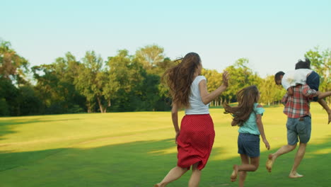 Familie-Läuft-Im-Feld.-Glückliche-Kinder-Und-Eltern,-Die-Mit-Ball-Auf-Der-Wiese-Spielen