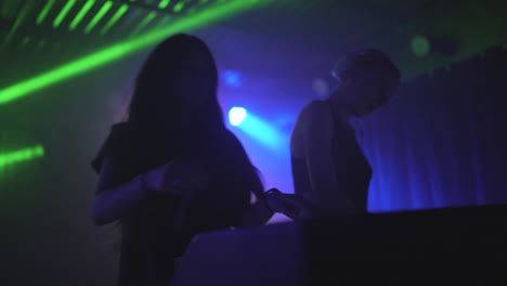 dos hermosas mujeres jóvenes dj tocan la música en la consola de mezcla en el club nocturno