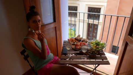 mujer disfrutando de una comida con una vista de la ciudad en un balcón