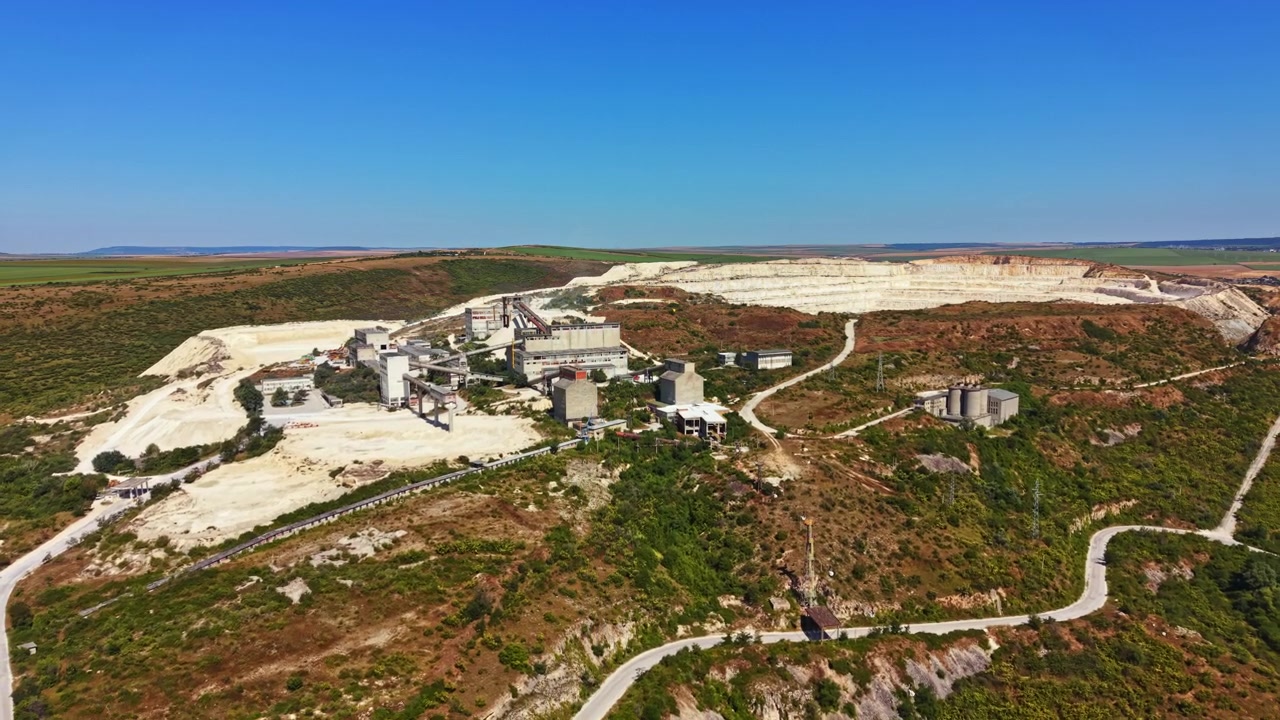 Vista de um grande local industrial com edifícios e máquinas perto de uma colina durante o dia claro