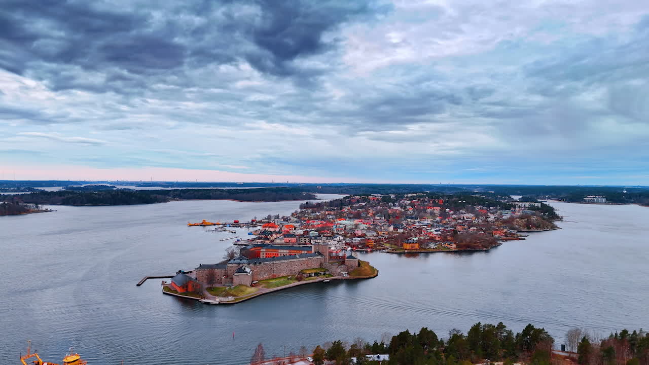Vista de un pequeño pueblo isleño cerca del agua en el norte de Europa bajo cielos nubosos. Un pequeño pueblo se asienta en una isla rodeada de agua, con barcos cerca y edificios a la vista bajo cielos nubosos