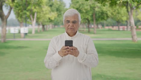 Indian-old-man-chatting-on-phone-in-park