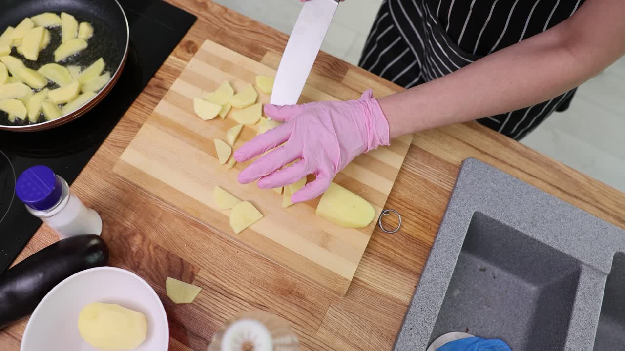 Hands slicing potatoes for cooking in a kitchen