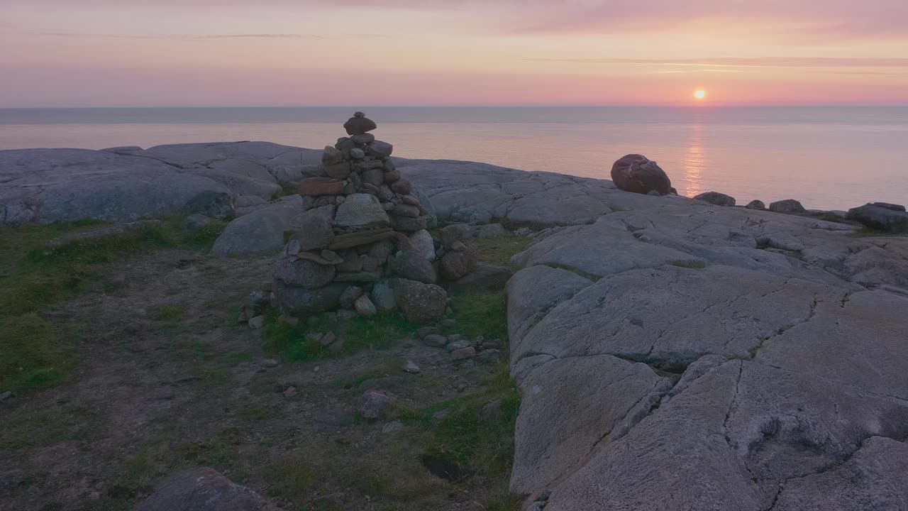 Sunset at Sheigra, Scotland. Camera pans right across a cairn with the glowing Atlantic horizon behind rugged coastal rocks