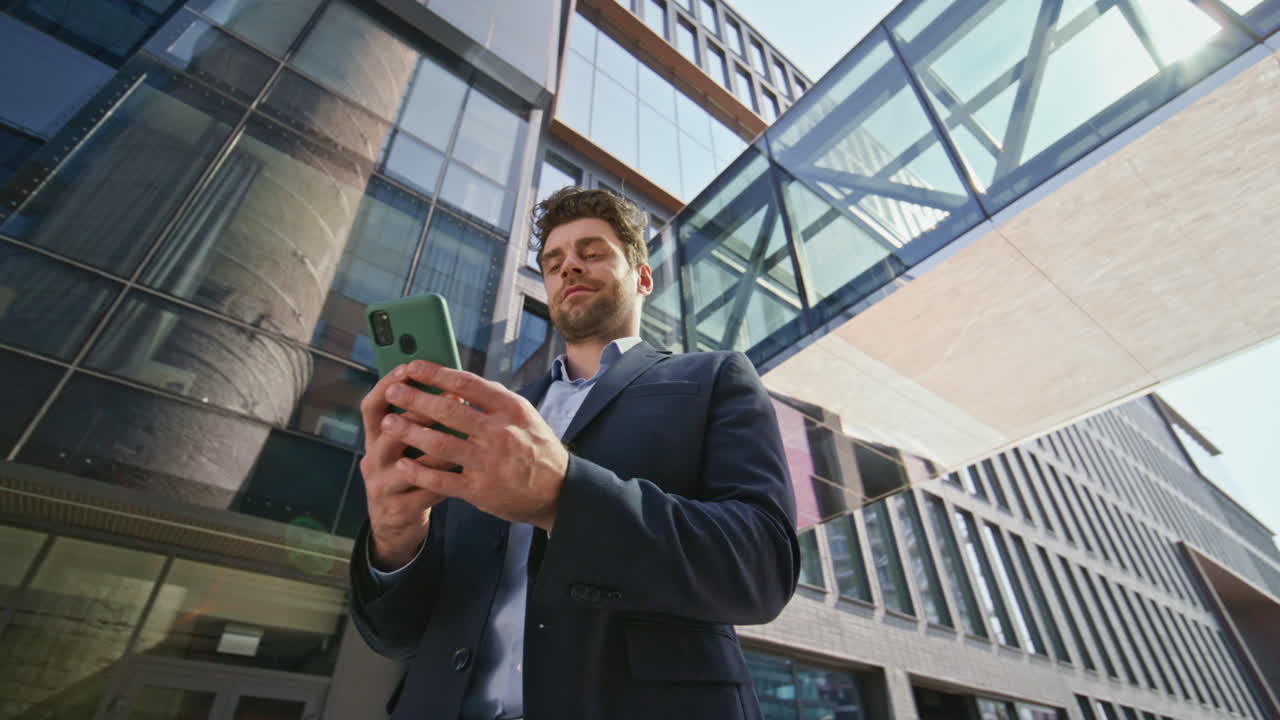 elegante director comprobando el mensaje del teléfono móvil en el área de la ciudad moderna. hombre sonriendo