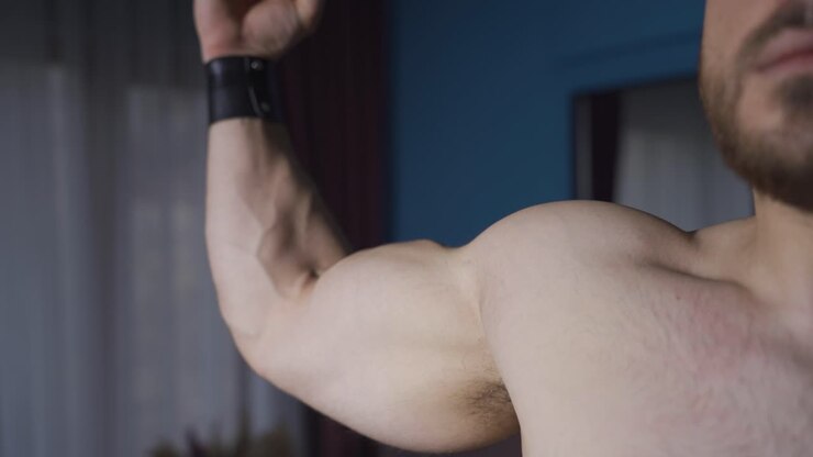 Muscular man practicing pose in a dark environment.