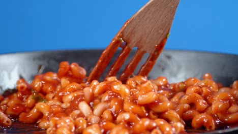 with spatula mix boiled pasta cavatappi with tomato sauce.