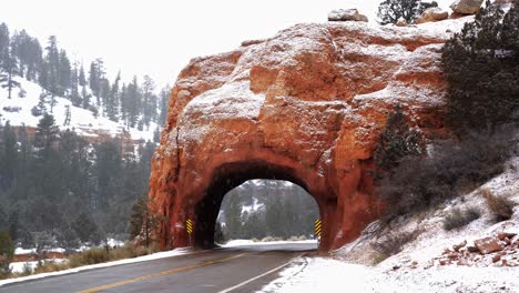 un hermoso túnel de arco de roca roja natural en medio de una pequeña carretera en el sur de utah