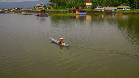 Cámara-Lenta---Pescador-Remando-En-Un-Bote-De-Madera-A-Través-Del-Lago---Lago-Rawa-Pening,-Indonesia