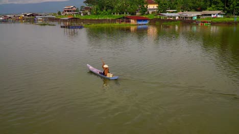 cámara lenta - pescador remando en un bote de madera a través del lago - lago rawa pening, indonesia