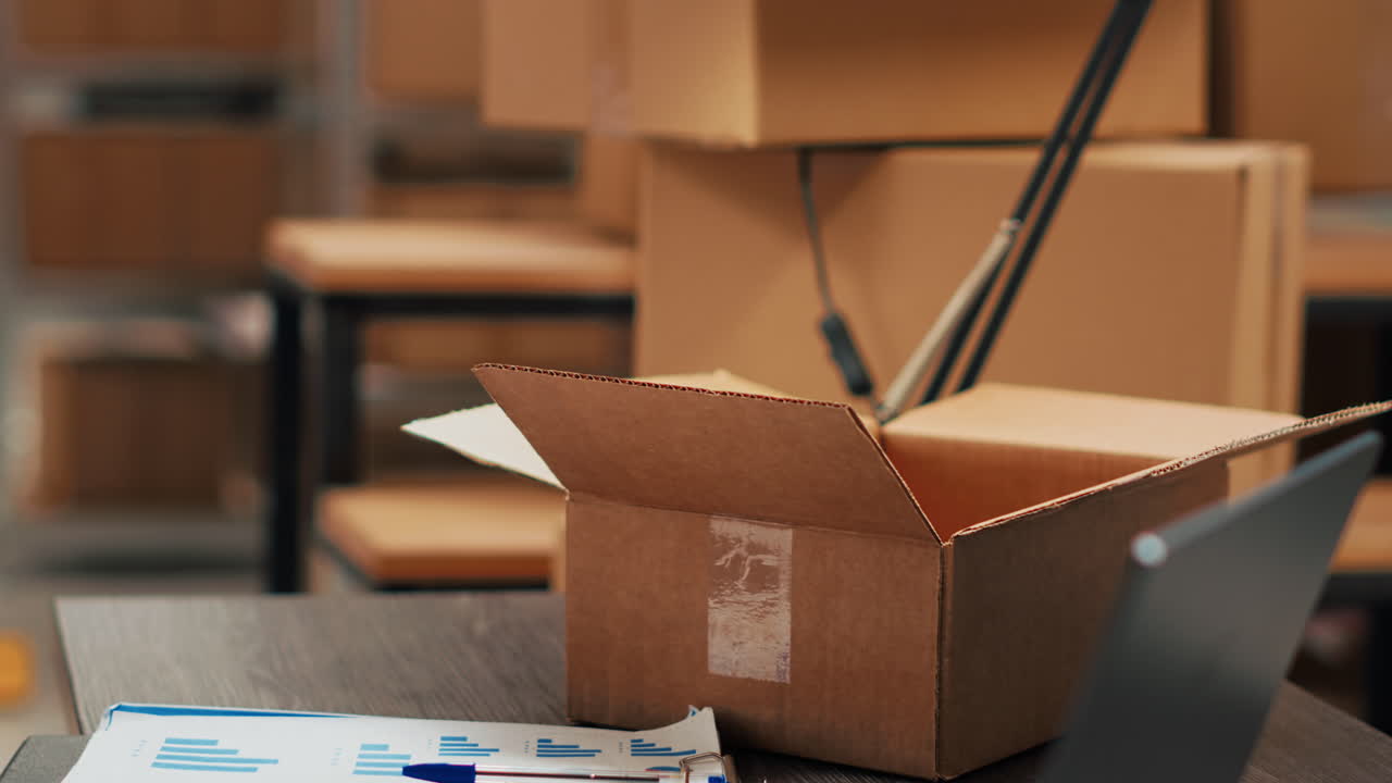 Open cardboard box with laptop and documents in a warehouse