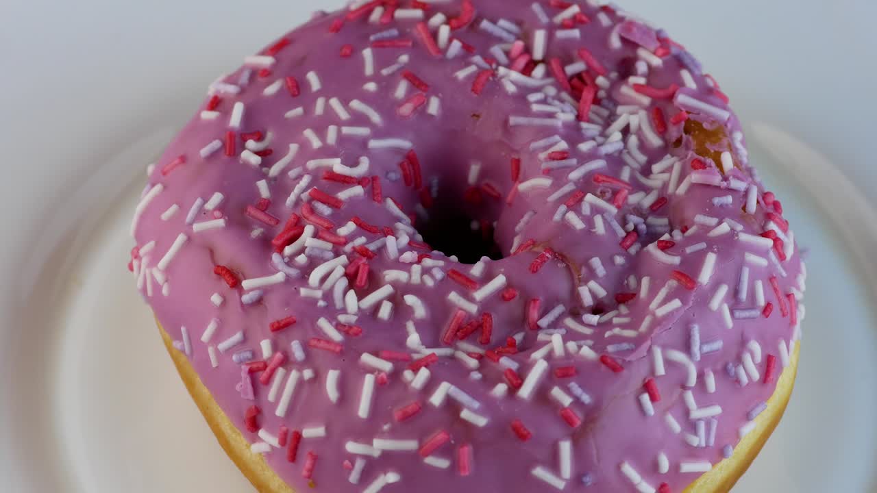 rosquilla recién horneada en un plato gira de cerca. pan productos de panadería tema. rosquilla esmaltada postre apetitoso. enfoque selectivo, profundidad de campo poco profunda