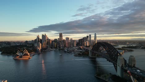 sydney harbour bridge and sydney opera house on sydney harbour during a cloudy sunset