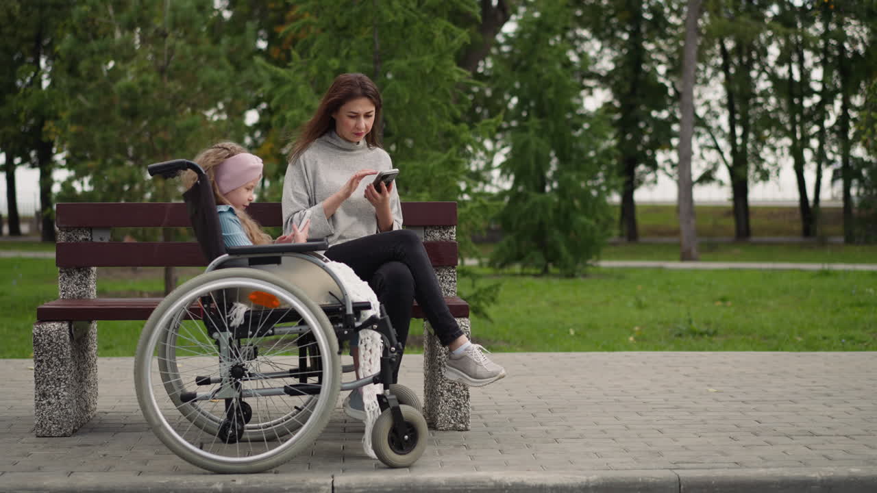 mujer chequea el correo electrónico mientras la niña mira videos en el teléfono inteligente
