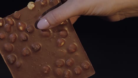 una barra de chocolate negro en la mano de una mujer en primer plano.