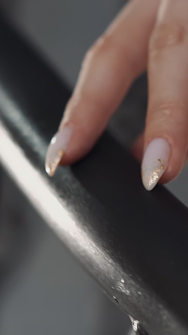 Bride with elegant manicure in sparkling white dress touches railing on staircase closeup. Wedding ceremony fashion trends. Marriage holiday