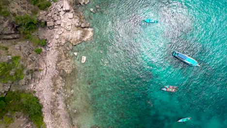 Drone-aerial-shot-of-rocky-bay-and-coral-reef-zooming-out-and-spinning-in-Koh-Tao,-Thailand