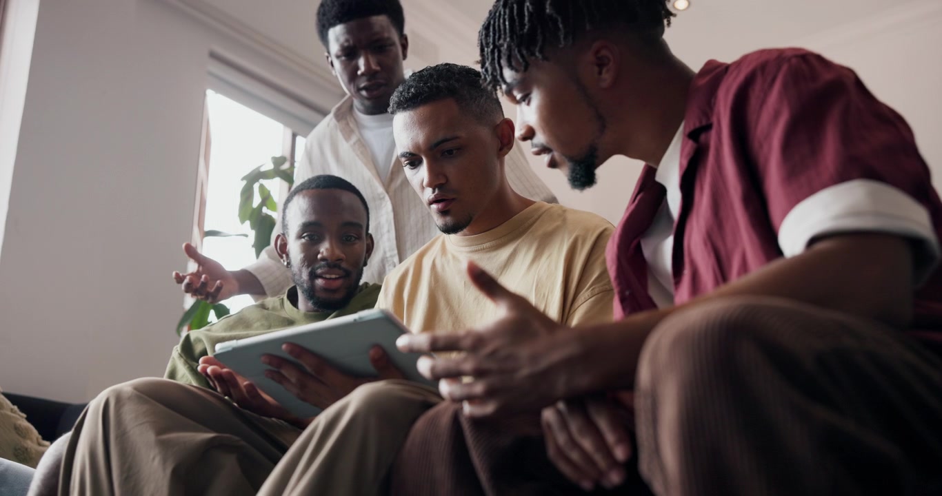 Group of Young Men Collaborating on a Tablet in a Living Room