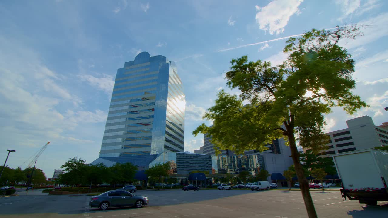 Low, wide dolly stabilized gimbal shot of several large sleek corporate skyscrapers with a striking blue sky and vivid clouds.