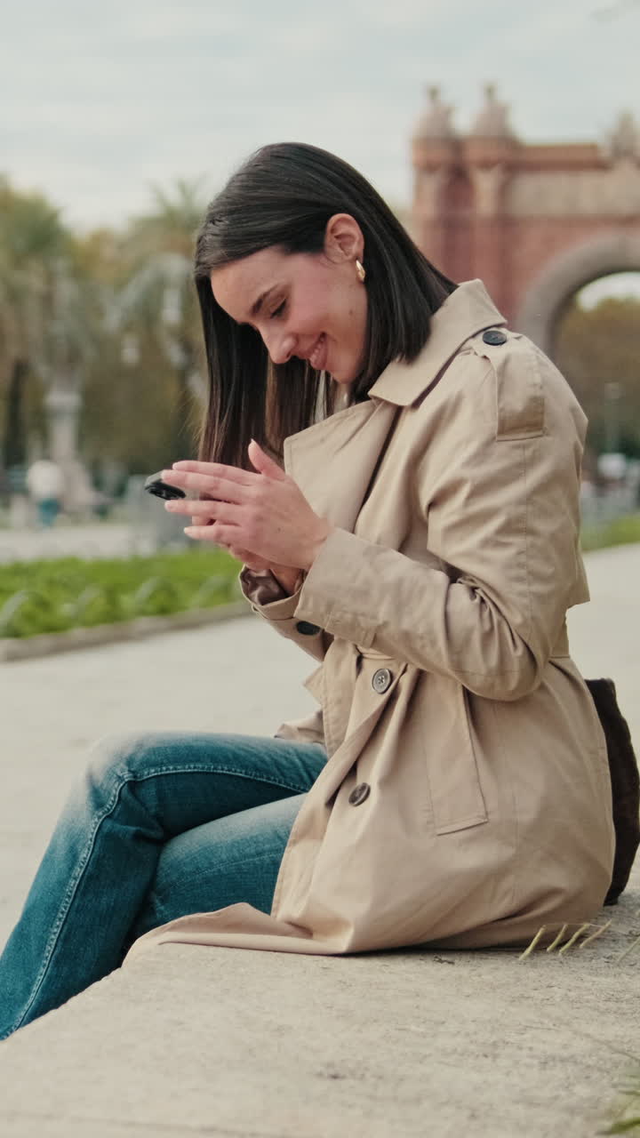 Giovane donna seduta nel parco e usa lo smartphone