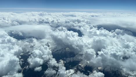 aerial view from a cockpit of the alps covered with a few snow and some cumulus