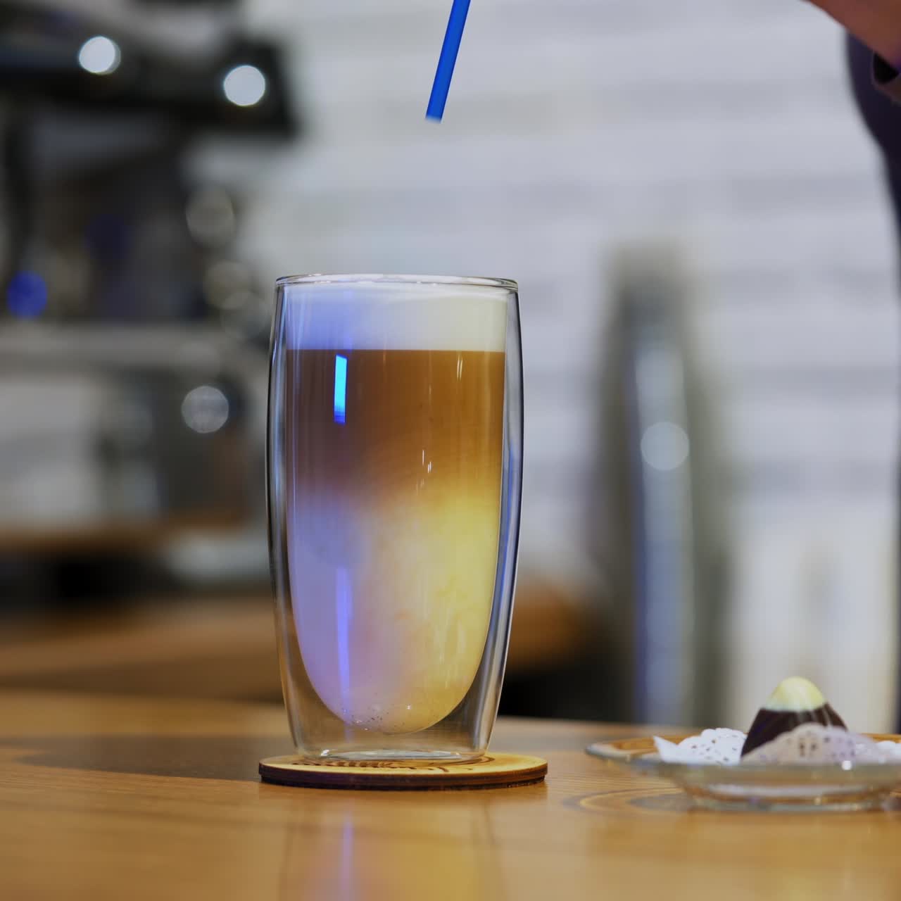 Serving beverage. Tasty dessert on the table. Woman puts straw into a glass of fresh drink and some sweet on a plate. Close-up.