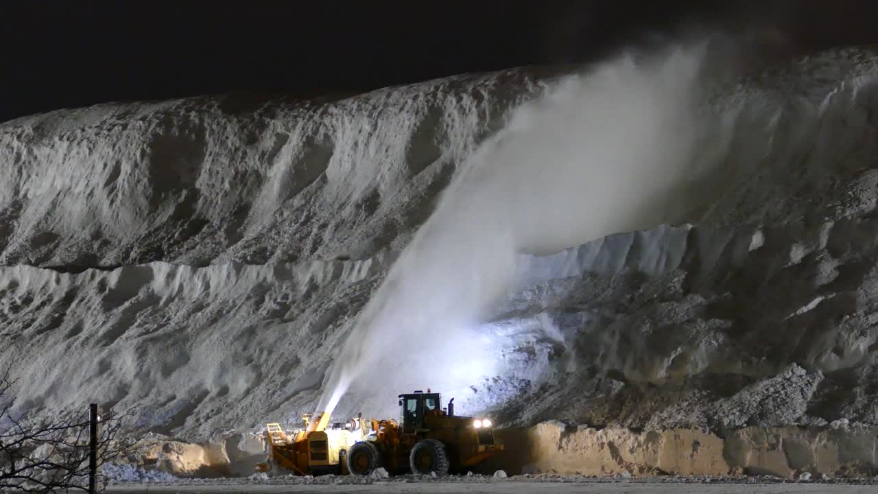 Heavy machinery clearing a pile of snow on a street in Montr&eacute;al, Quebec, Canada
