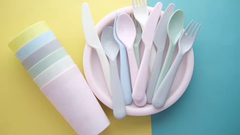 colorful plastic plates, glass and cutlery on table