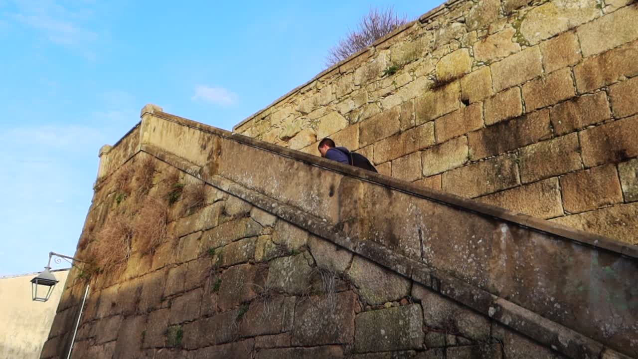 vista de ángulo bajo de un hombre caucásico escalando una escalera de piedra arrasada hacia jardim do morro