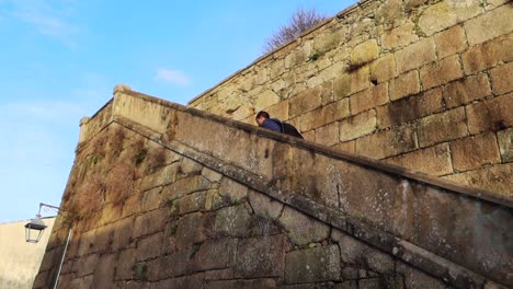 Low-angle-view-of-caucasian-man-climbing-washed-out-stone-stairway-towards-Jardim-do-Morro