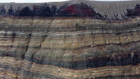 pan across sedimentary rock strata on steep wall in volcano crater